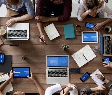 Group of people at a table with laptops and tablets