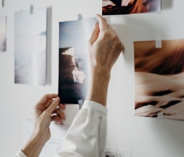 Person holding photos on a wall